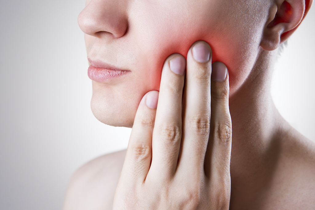 woman holding her jaw in pain